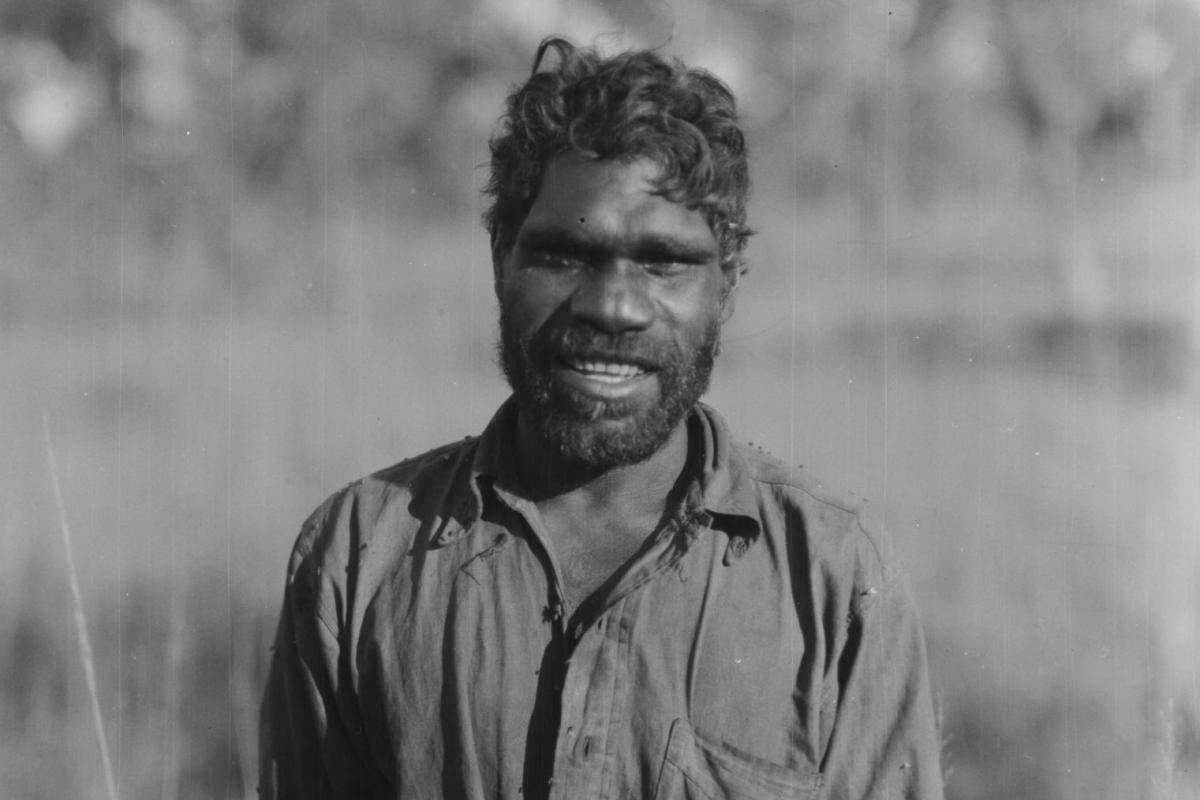 A smiling portrait of Ayaiga in an Australian bush setting. 