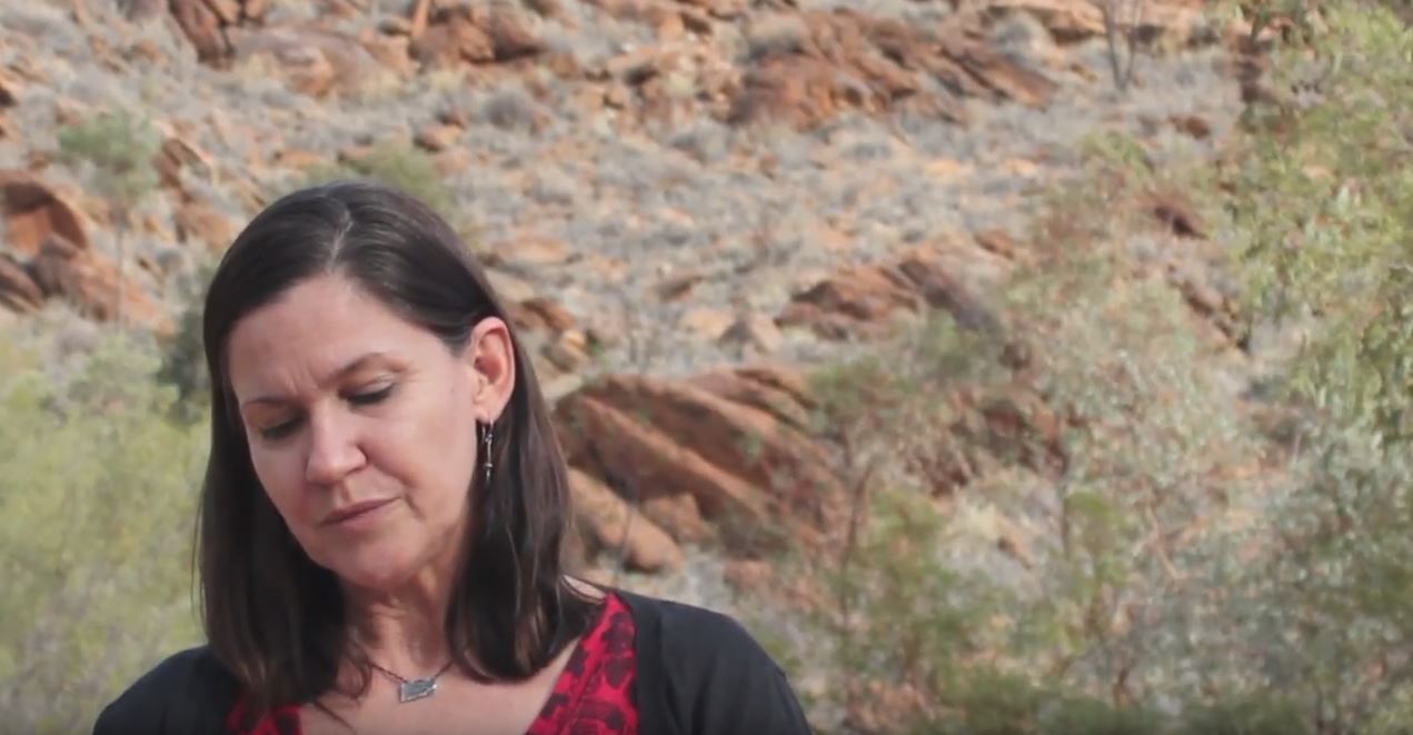 Leni Shilton presenting in an outdoor setting, red rocks behind her. 